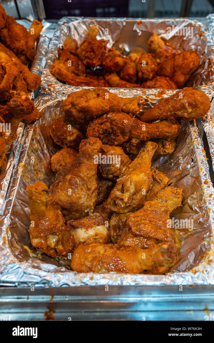 Delicious fried chicken drumsticks in aluminum tray at food market