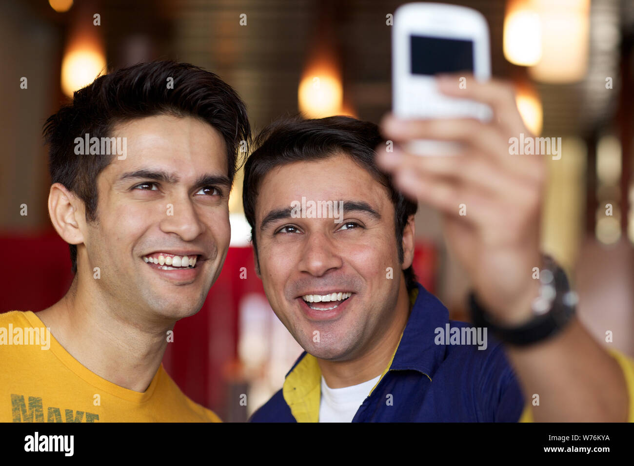 Indian friends taking a picture of themselves with a mobile phone in a restaurant Stock Photo