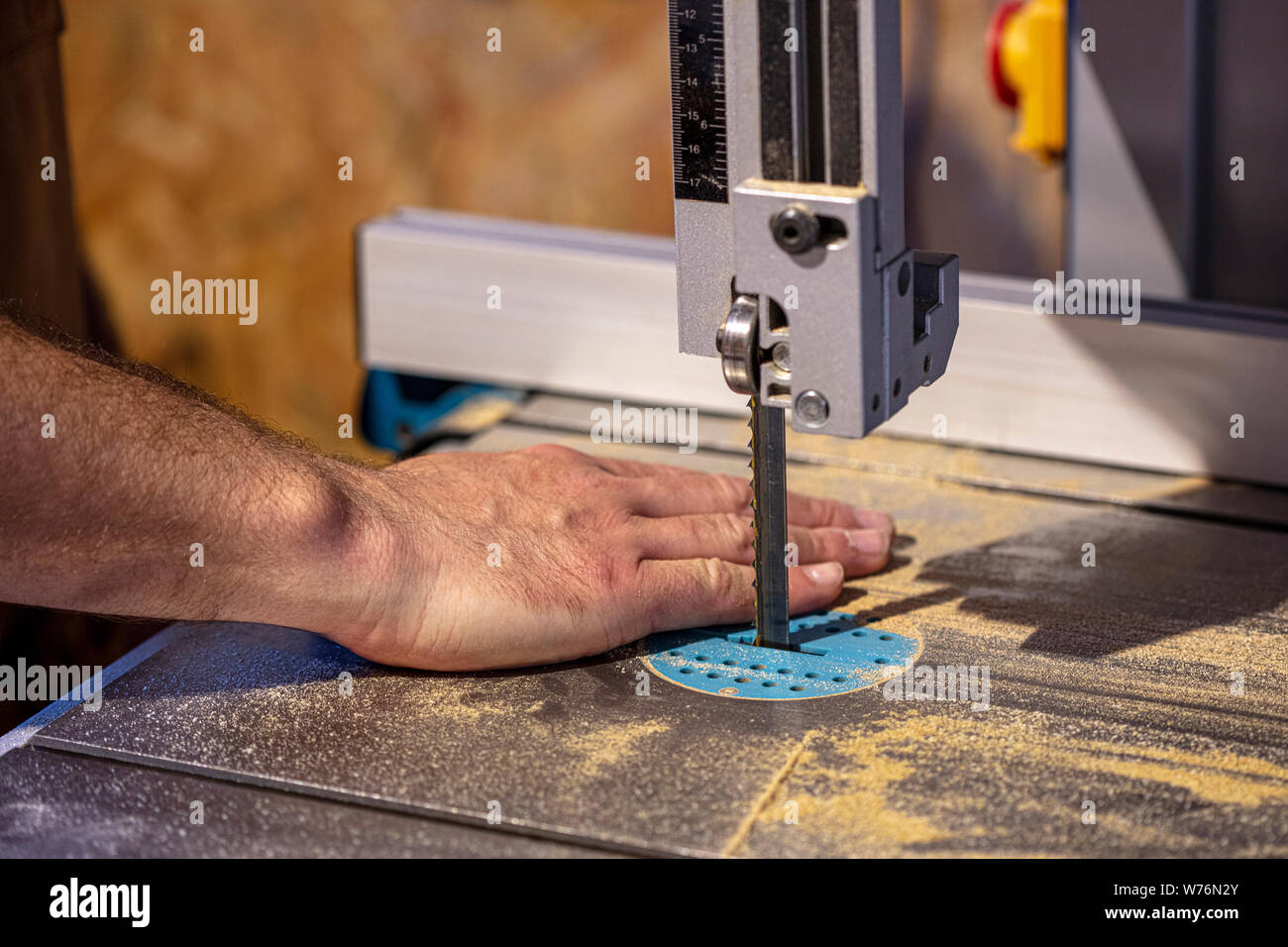detail of a carpenter's band saw and a hand placed in the wrong and dangerous position. work safety concept. Stock Photo