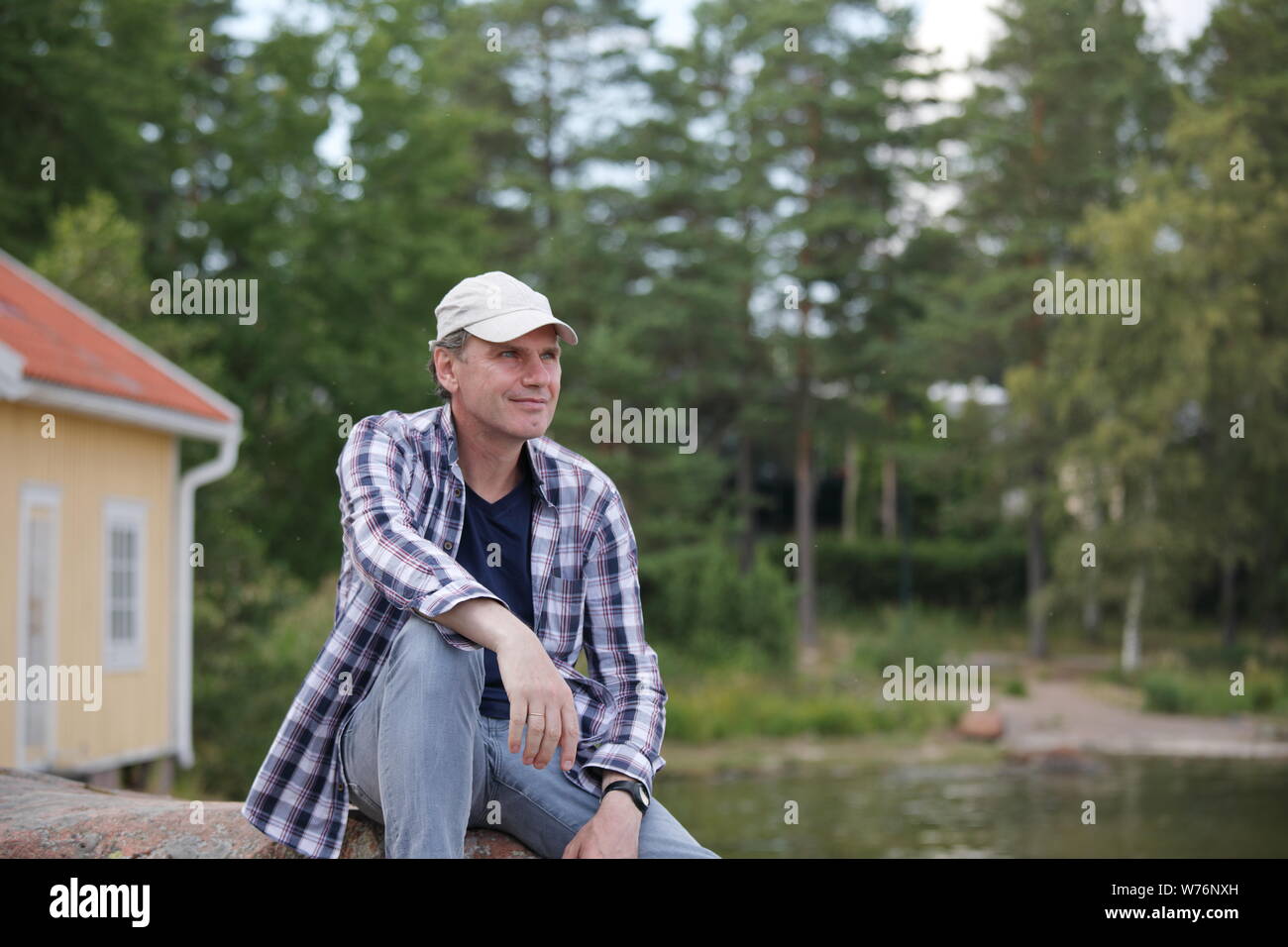 Man resting on a stone on the coast of Baltic sea in Finland Stock Photo