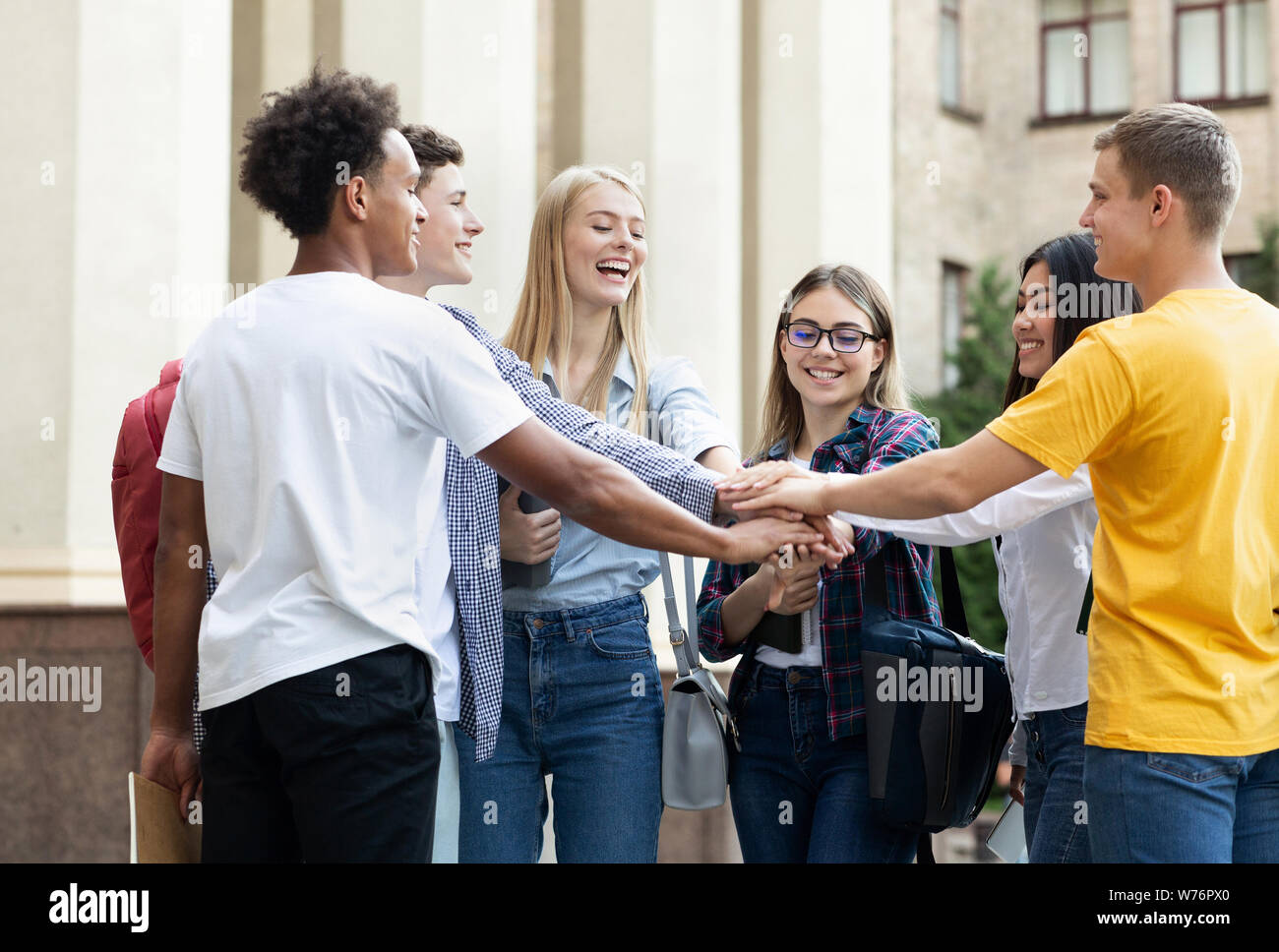 Ready to pass exams. Students stacking hands together Stock Photo
