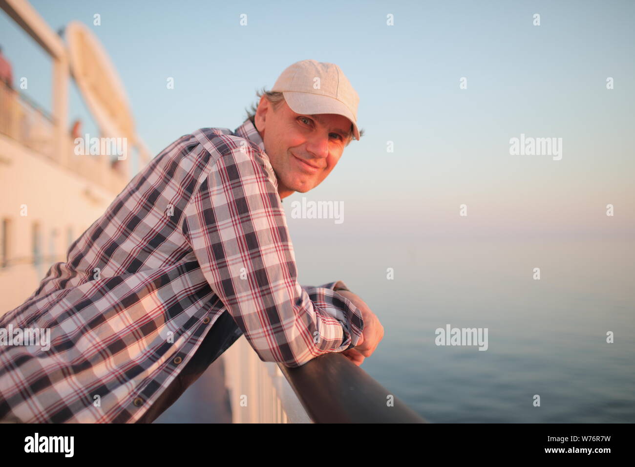 Man admires the sunset sea on the deck of a cruise ship Stock Photo