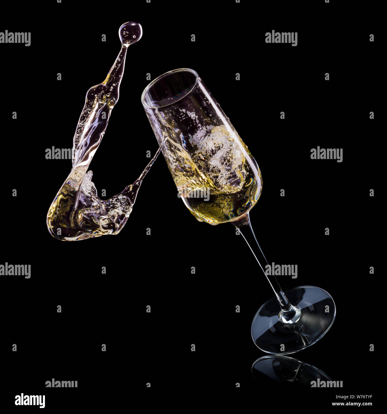 Glass for champagne with bubbles and splashes isolated on black