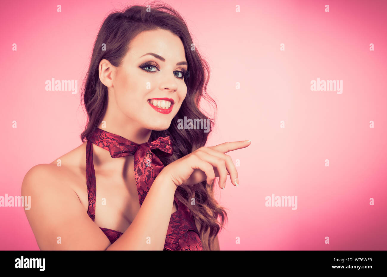 Beautiful young woman smiling and pointing.  Ideal for advertising your message Stock Photo