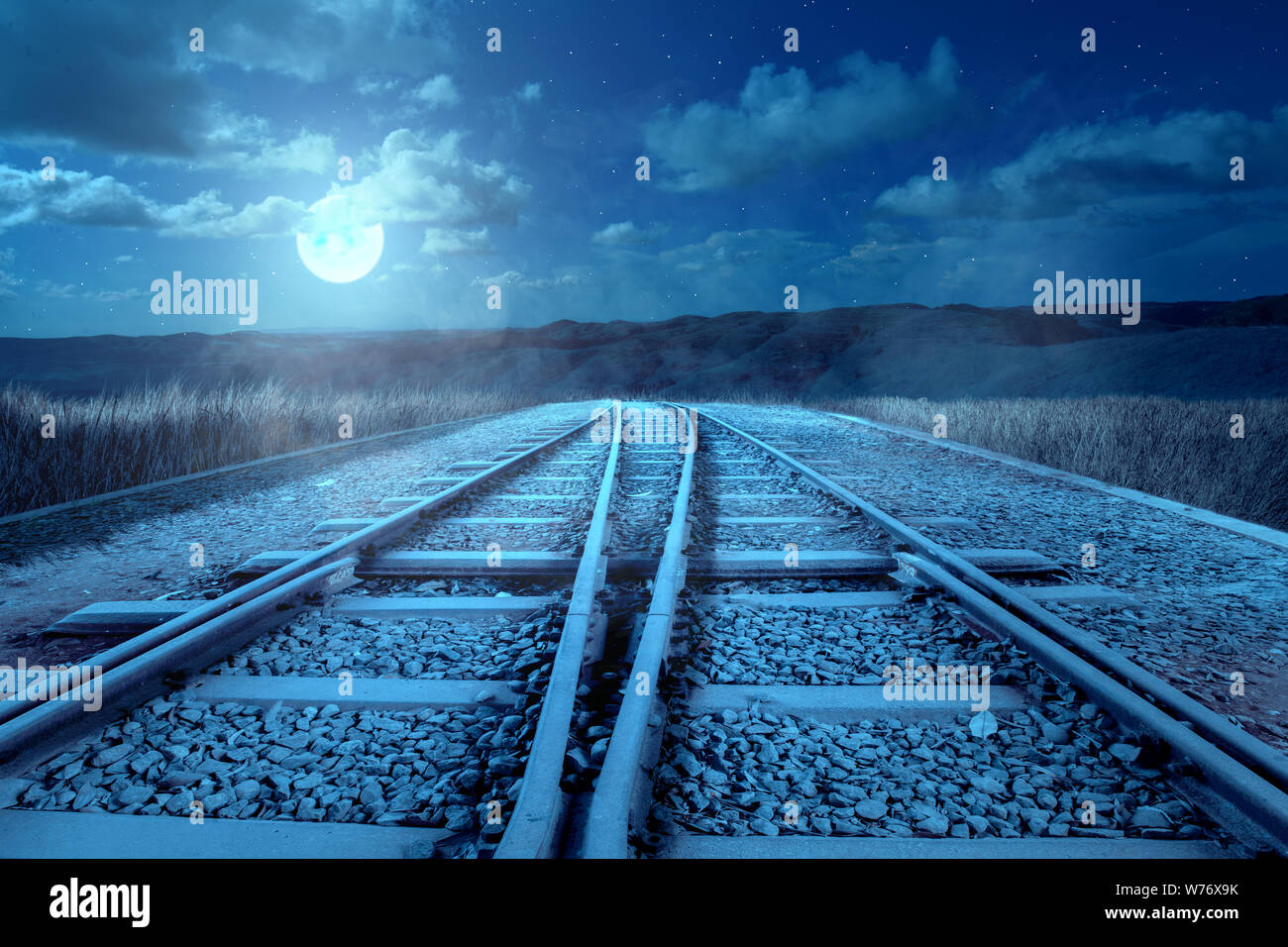 The crossing of a railroad track on the hills with a scary night scene. Halloween background Stock Photo