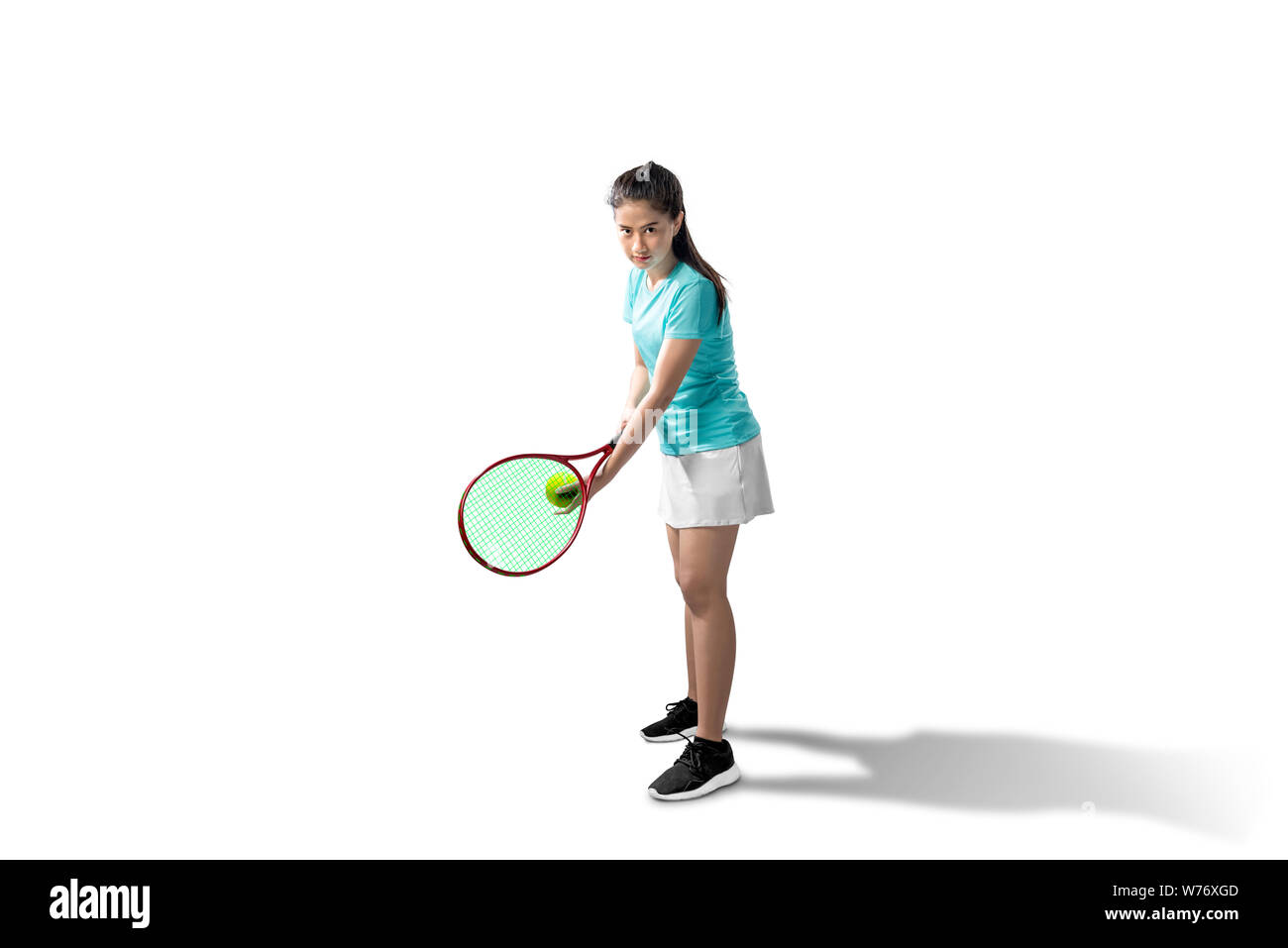 Asian woman with a tennis racket and ball in her hands ready in serve position isolated over white background Stock Photo