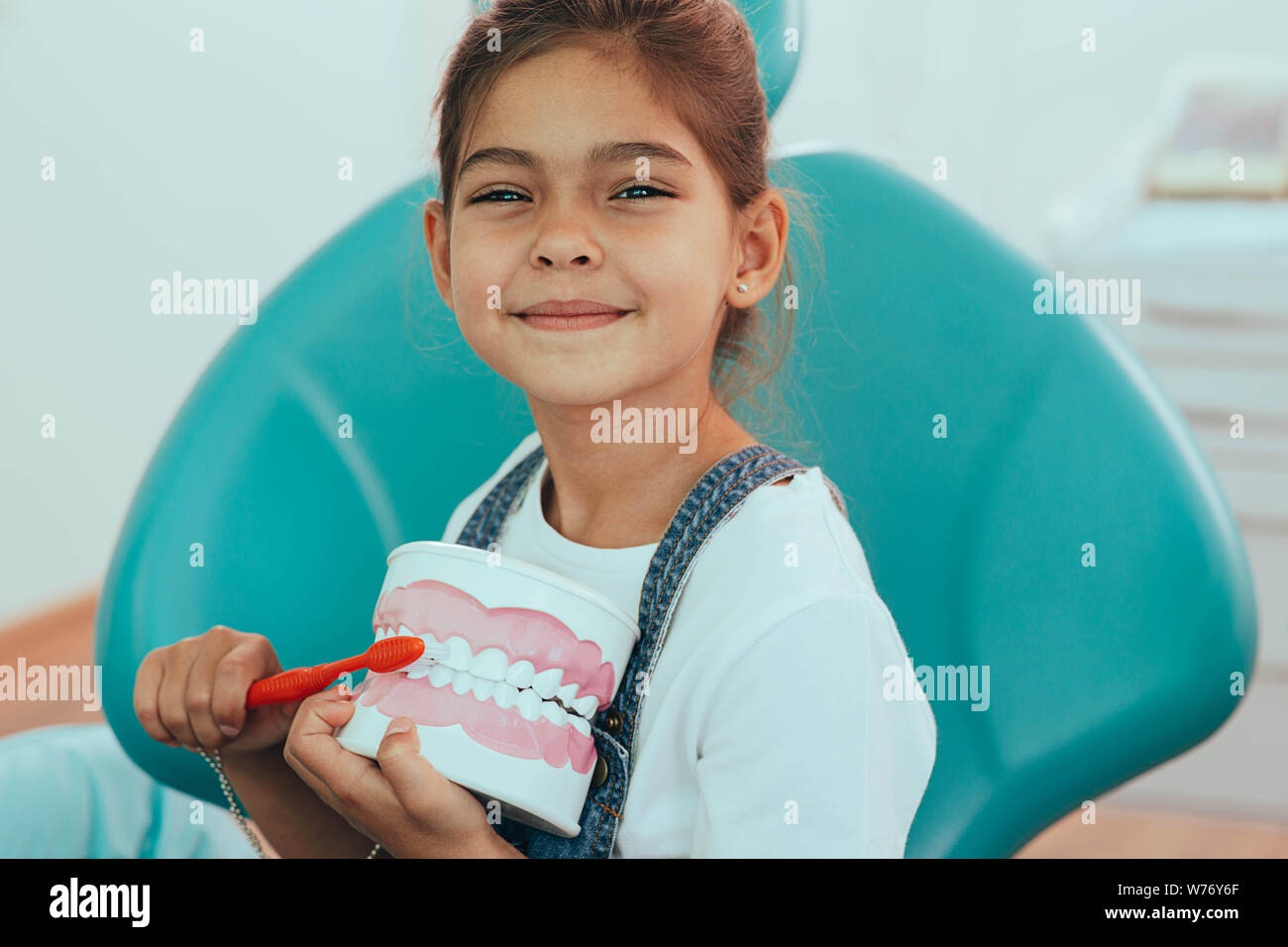 Cute little girl with human jaw model sitting in dentist's chair . teeth hygiene, brushing teeth Stock Photo