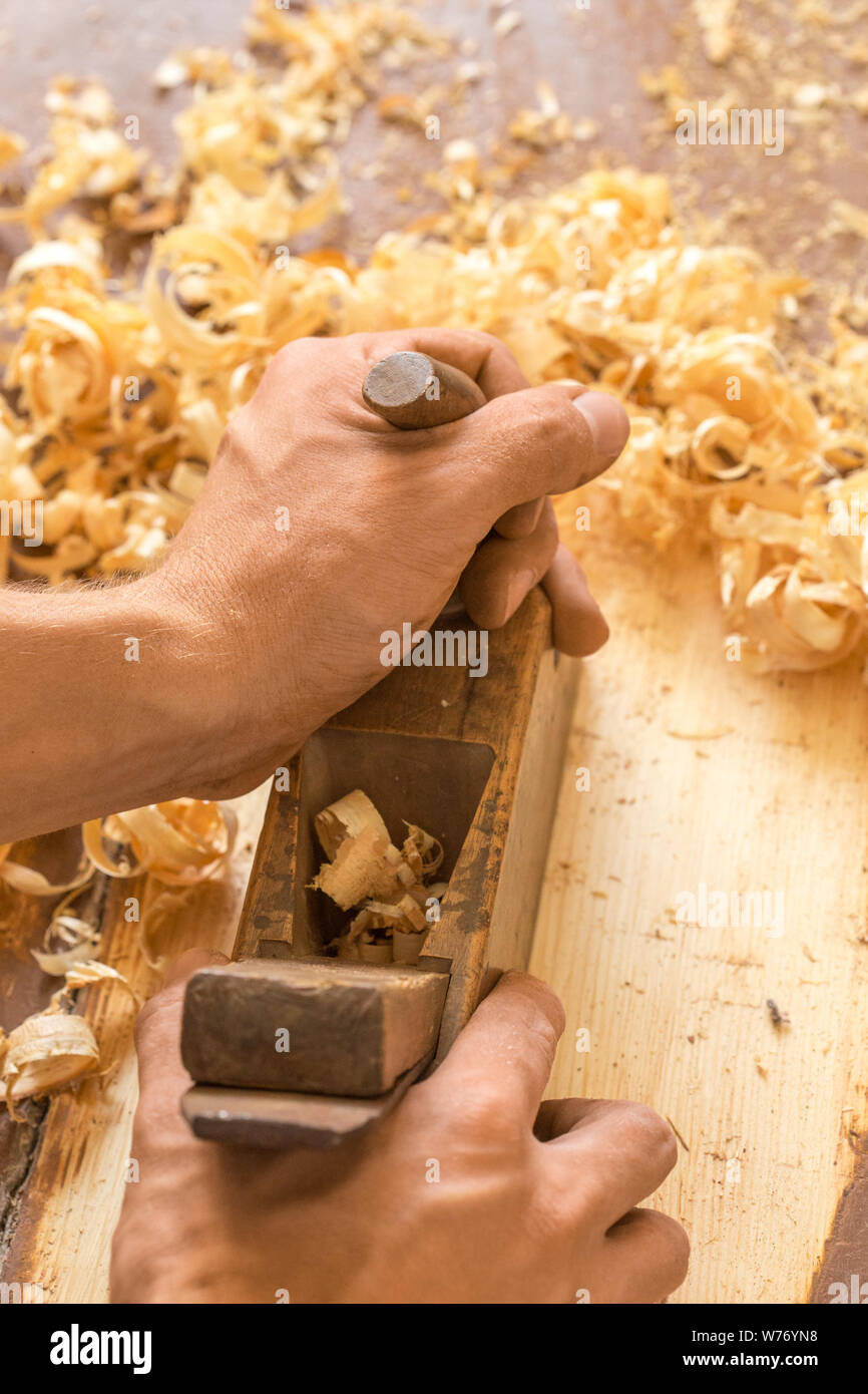 Wooden hand plane. Closeup of woodworker's hands shaving with a plane in a joinery workshop Stock Photo