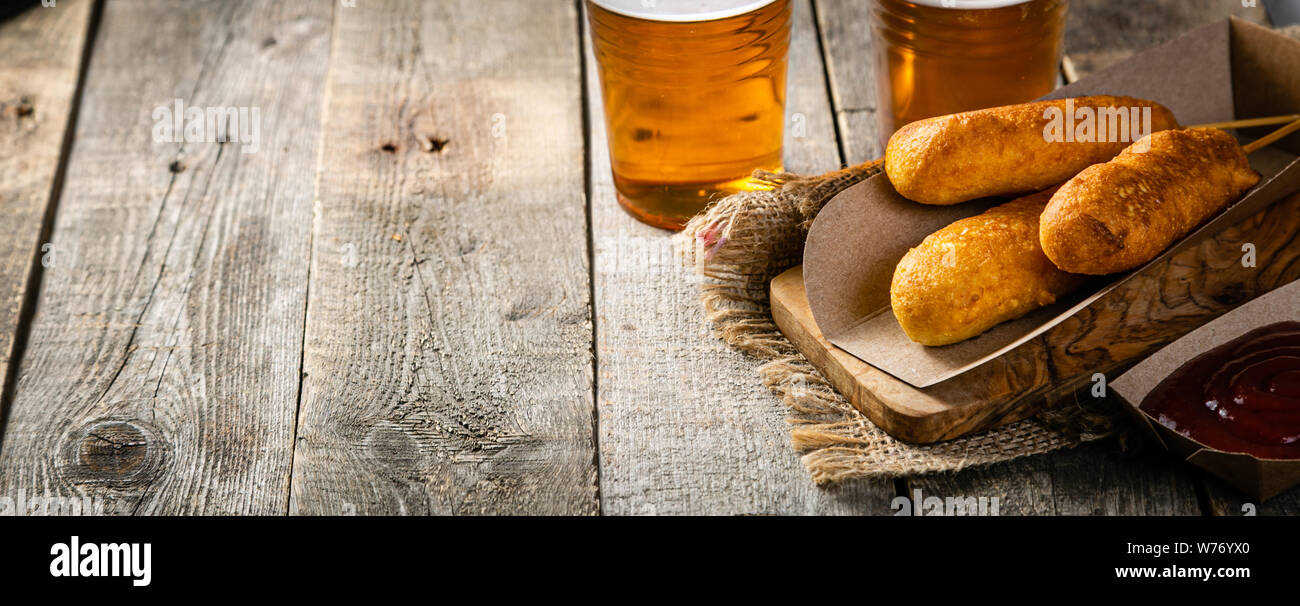 Corn dogs and beer on rustic background Stock Photo