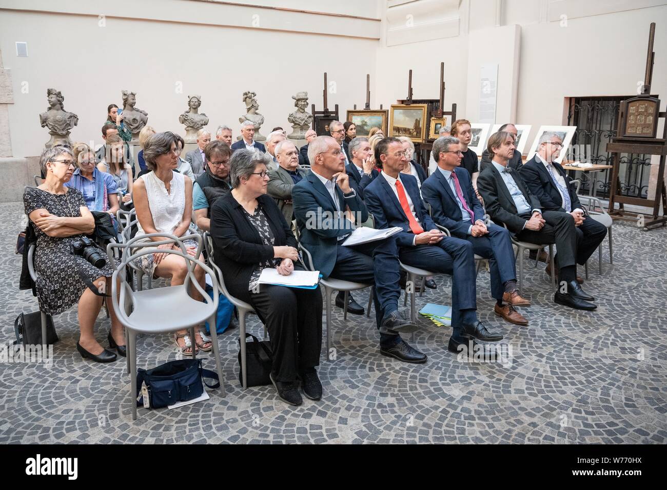 Munich, Germany. 05th Aug, 2019. Participants in the event for the restitution of nine Nazi looted works of art sit in the courtyard of the Bavarian National Museum. Five paintings, three colour engravings and a wooden panel had been confiscated by the Gestapo in November 1938. The Munich collections have now returned the works to the heirs of Julius and Simone Davidsohn from Munich. Credit: Sina Schuldt/dpa/Alamy Live News Stock Photo