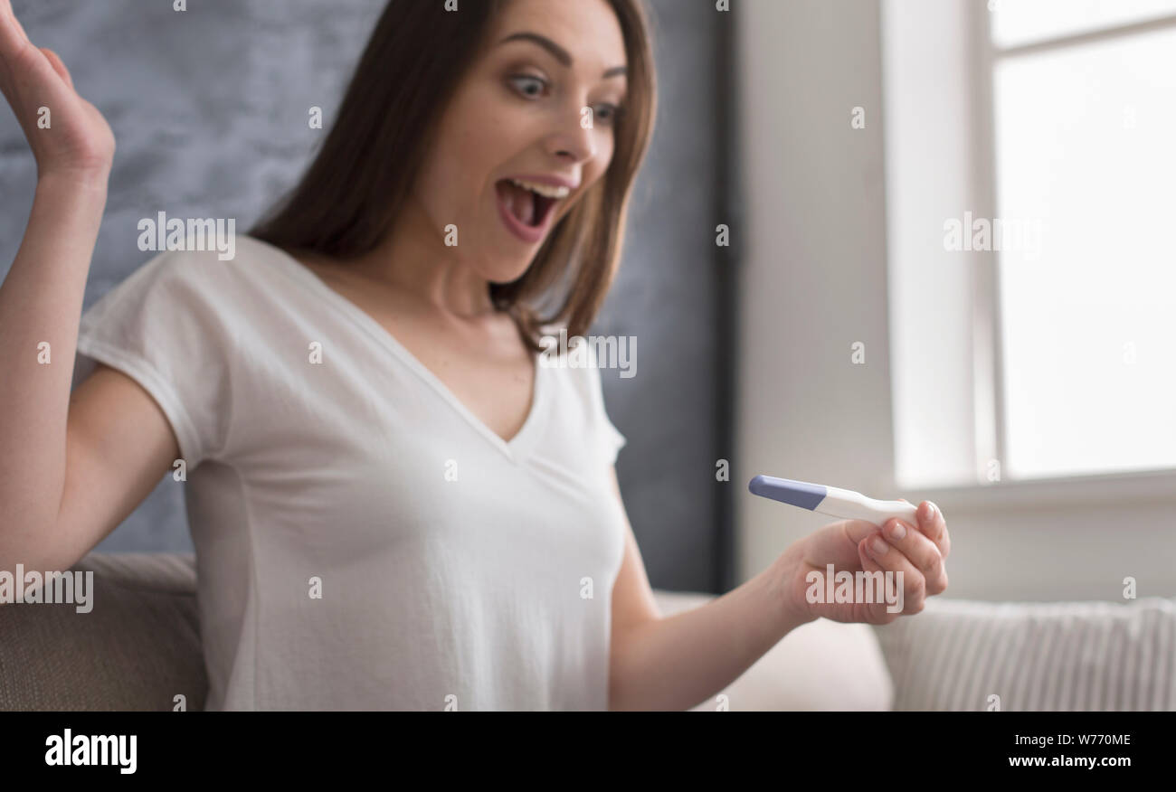 Happy young woman discovering positive result on pregnancy test Stock Photo