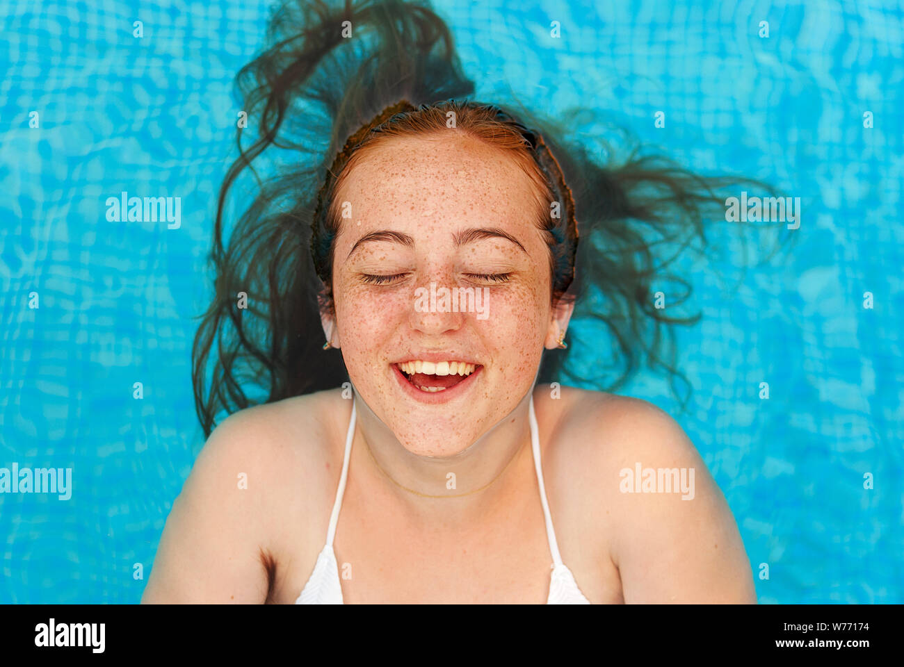 Teenager. Young woman with freckles into the swimming pool. Smiling. Stock Photo
