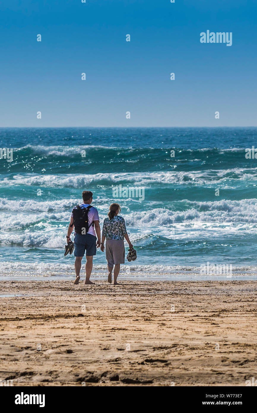 Holidaymakers standing on the shoreline gazing out to sea on Fistral Beach in Newquay in Cornwall. Stock Photo