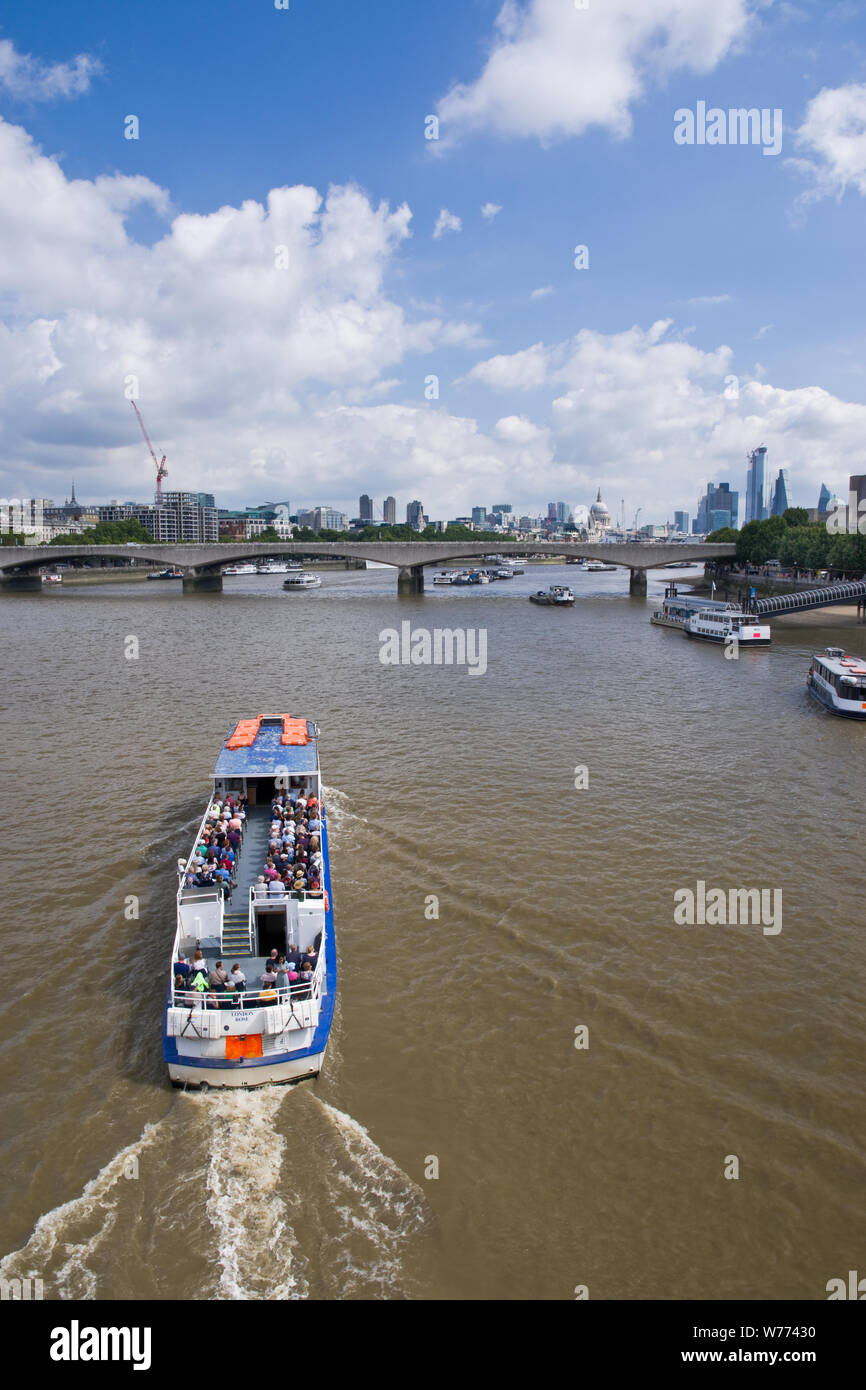 A tour boat carries sightseers along the river Thames in London, UK ...