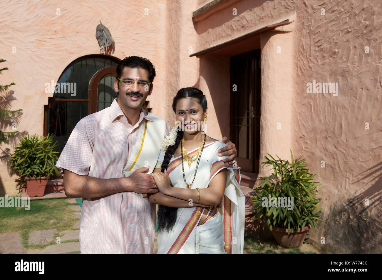 South Indian couple standing together in front of house Stock Photo - Alamy