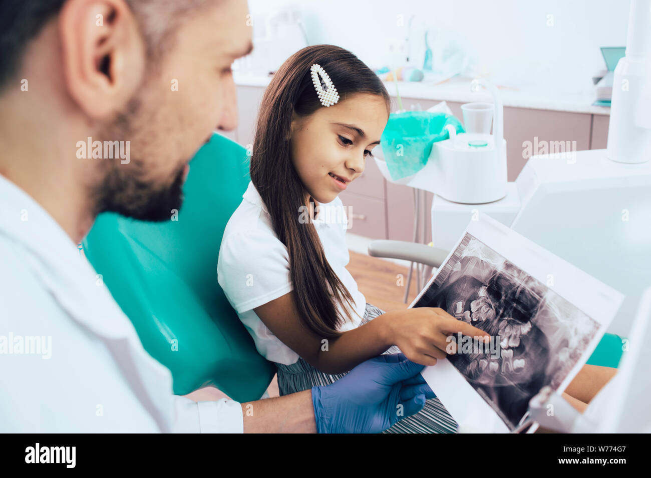 Dentist and mixed race little girl looking on x-ray teeth picture.Pediatric dentistry Stock Photo