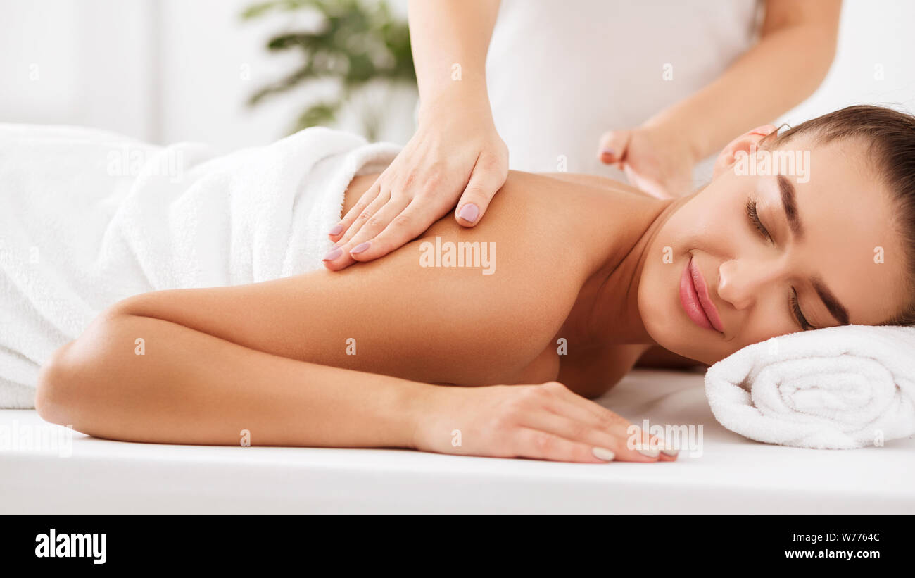 Masseur doing shoulder massage on woman body Stock Photo