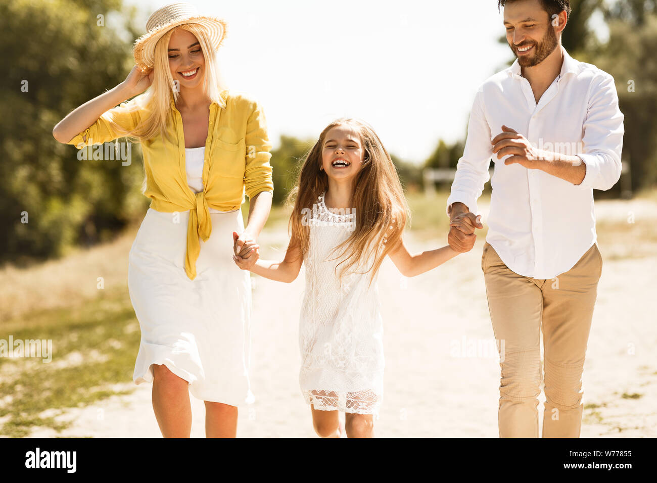 Happy parents walking with daughter, holding hands Stock Photo - Alamy