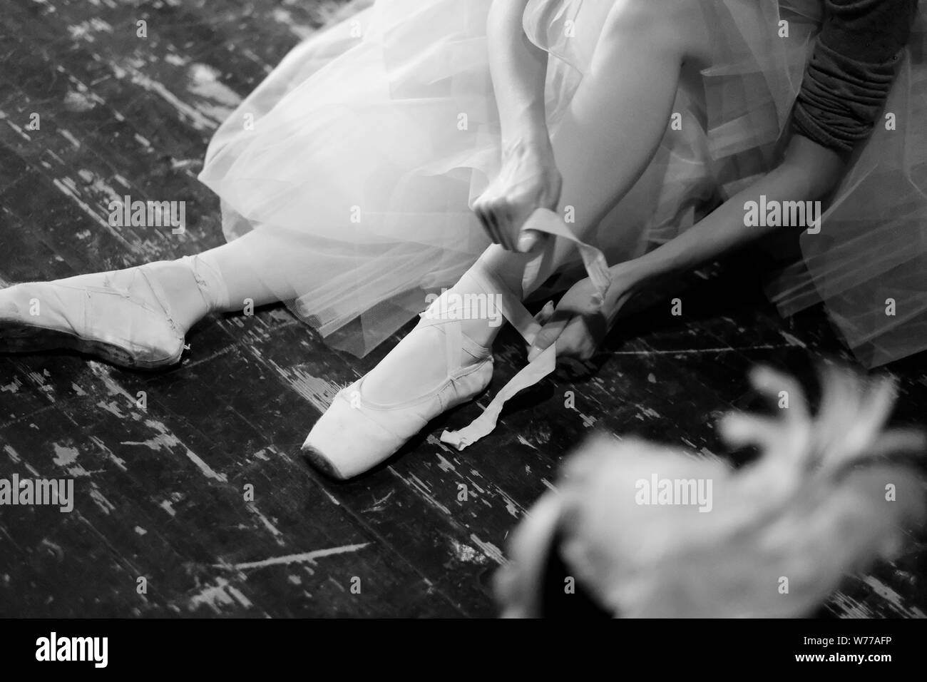 Ballerina is resting sitting on the floor in the rehearsal hall of the theater Stock Photo