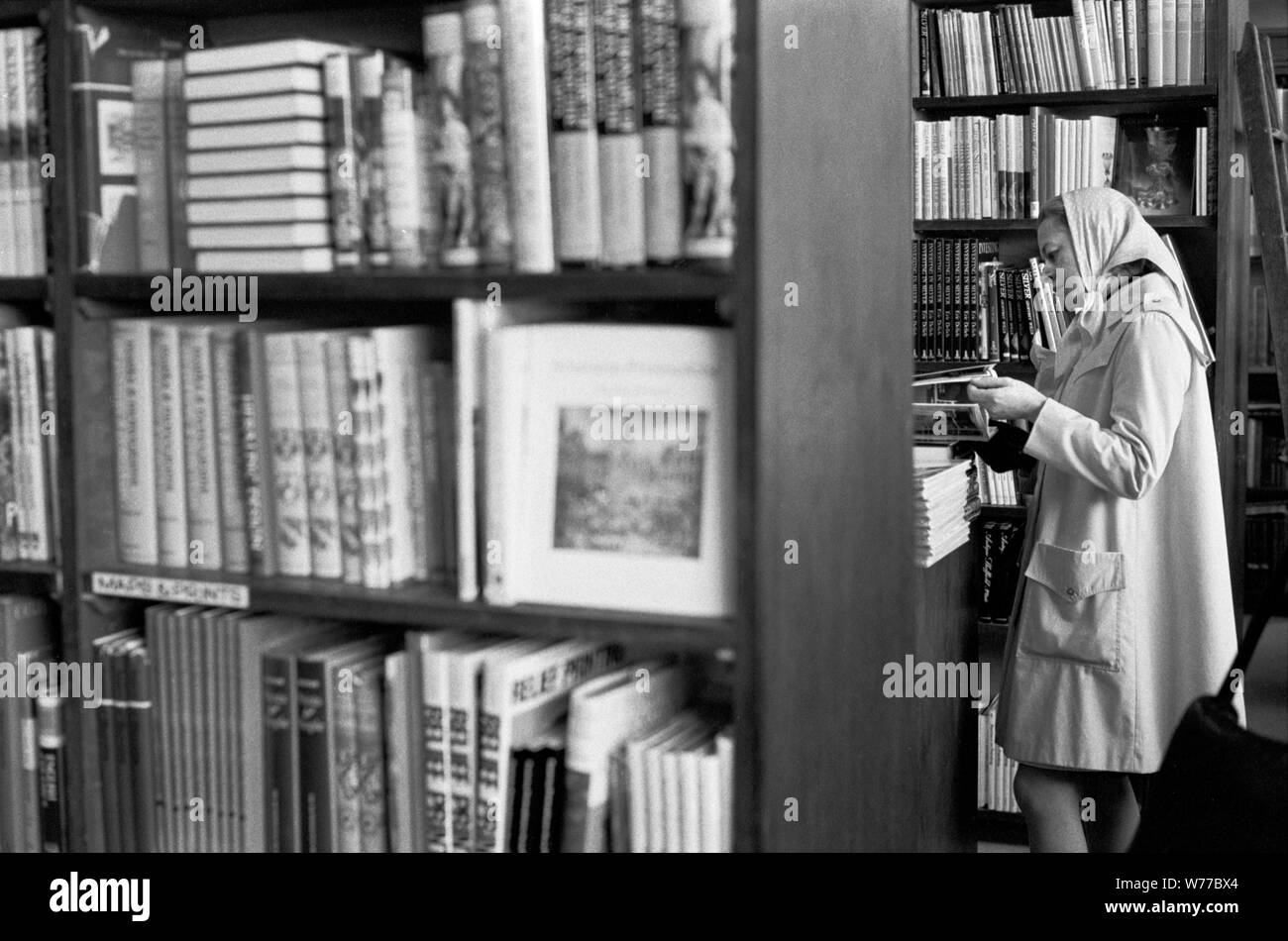 1970s book shop woman shopping making a decision browsing, buying deciding on which book to buy. 70S UK HOMER SYKES Stock Photo