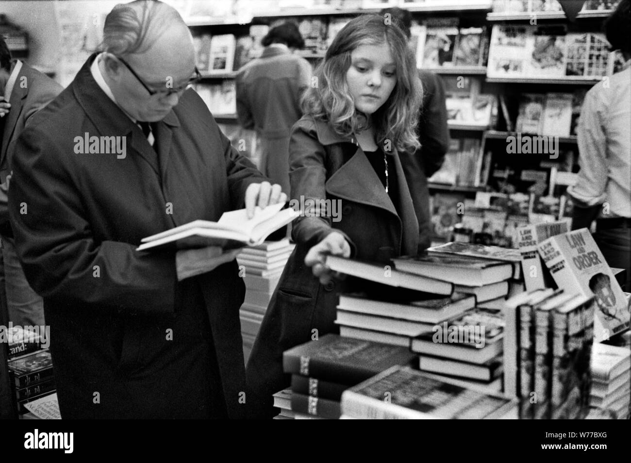 1970s busy crowded book shop people shopping browsing, teenage girl buying deciding on which book to buy. 70S UK HOMER SYKES Stock Photo