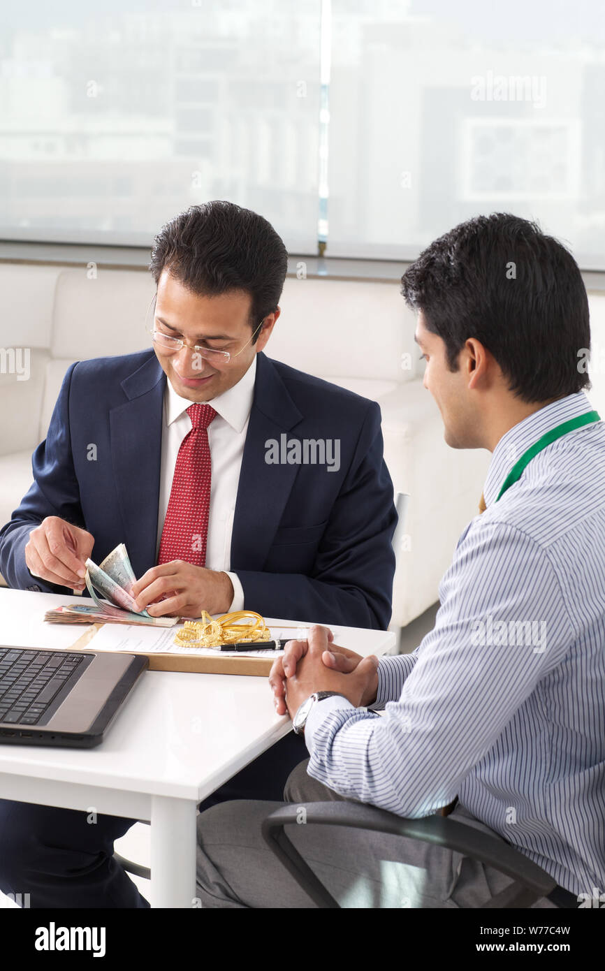Businessman counting money of gold loan Stock Photo - Alamy