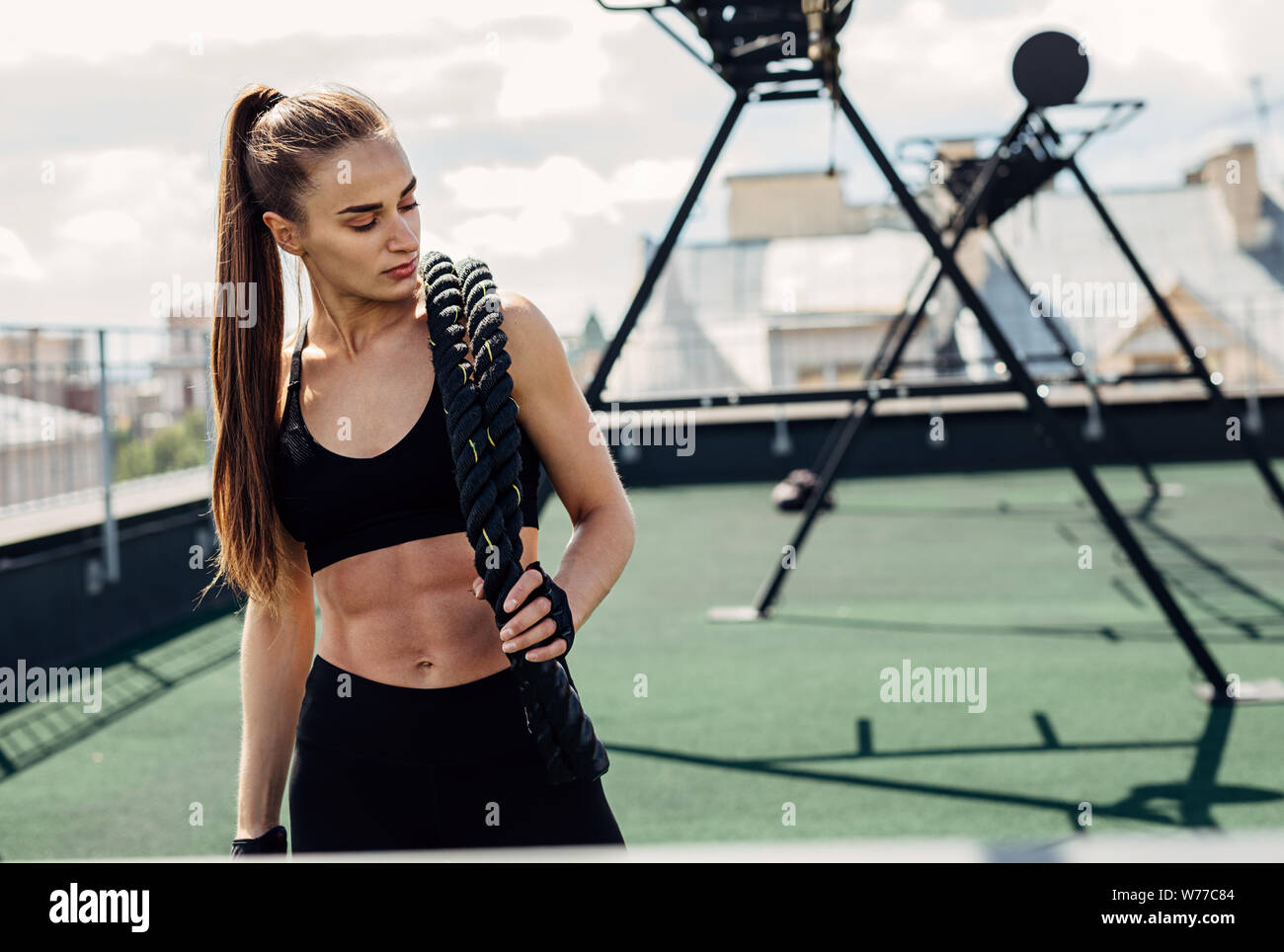 Woman looking down after intense physical training with battle ropes Stock Photo
