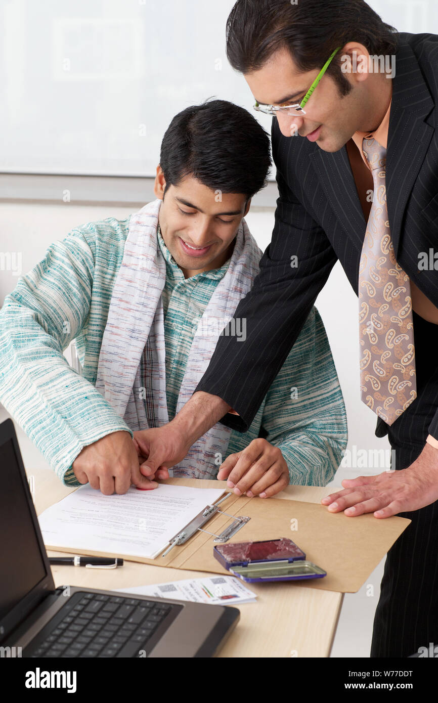 Bank teller taking thumb impression of a farmer on loan agreement Stock