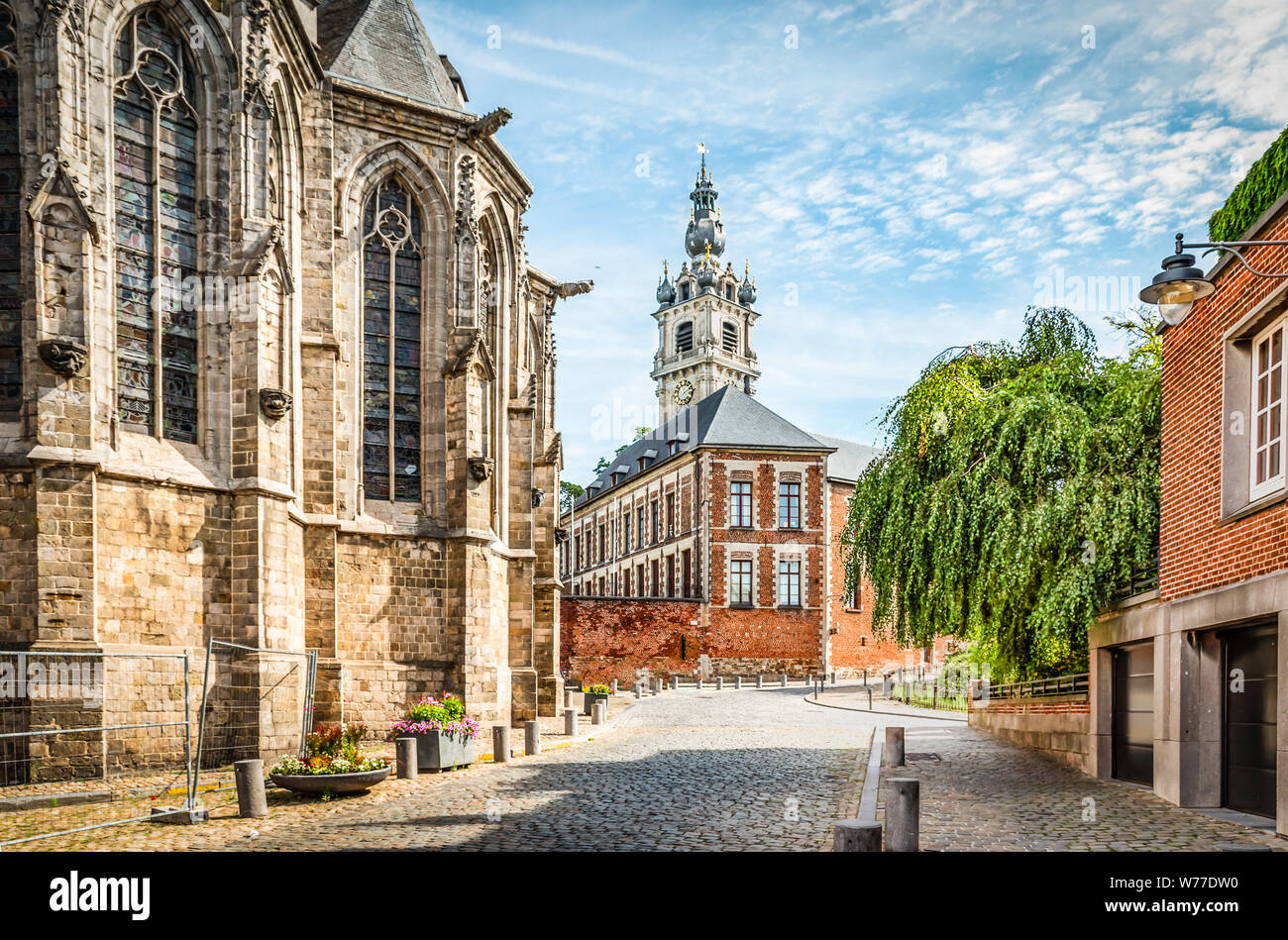Cobbled street with church and belfry tower in Walloon city center of Mons, Hainaut, Belgium. Stock Photo