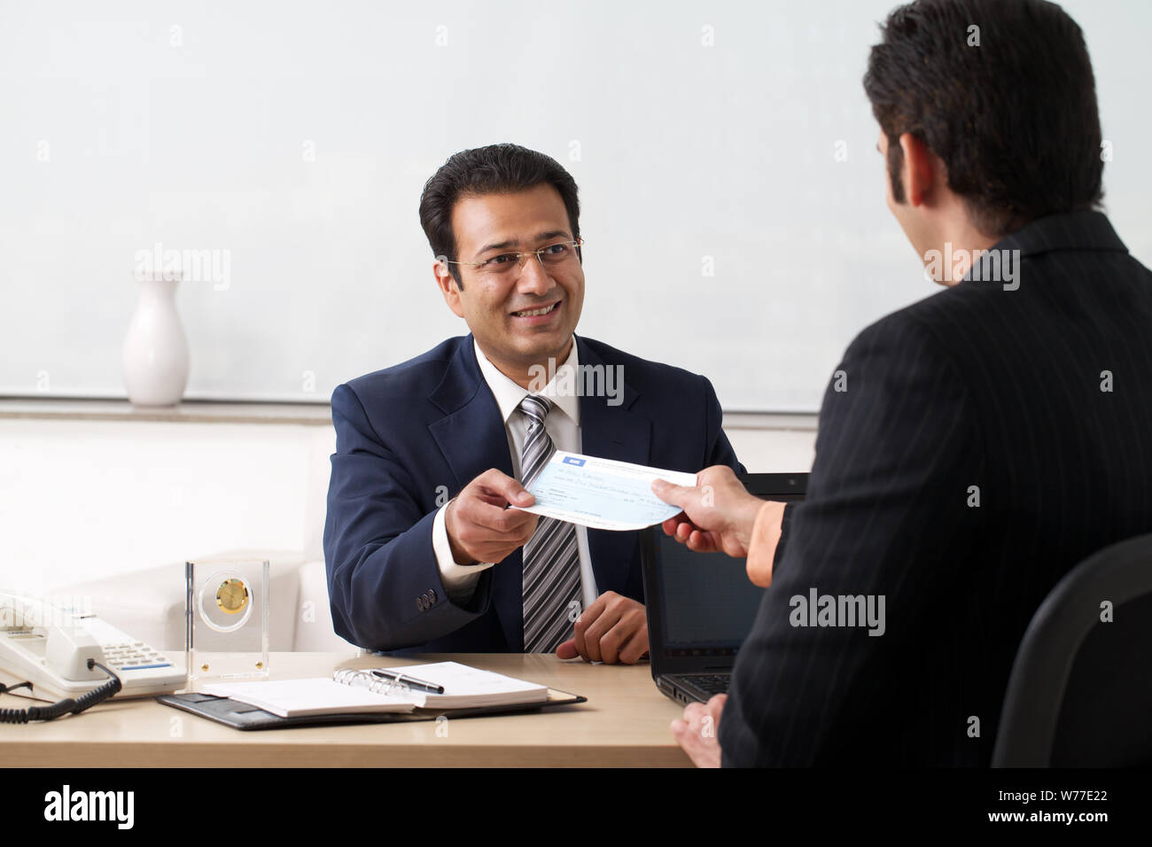 Bank manager giving cheque to his customer as loan Stock Photo - Alamy
