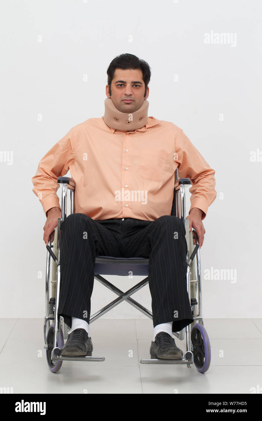 Young man sitting in a wheelchair and wearing neck brace Stock Photo
