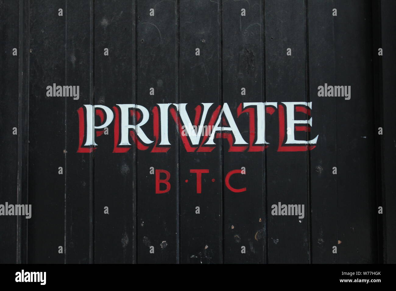 Image of black, wooden door with the word 'private' on in red and white letters, with 'B.T.C' underneath Stock Photo