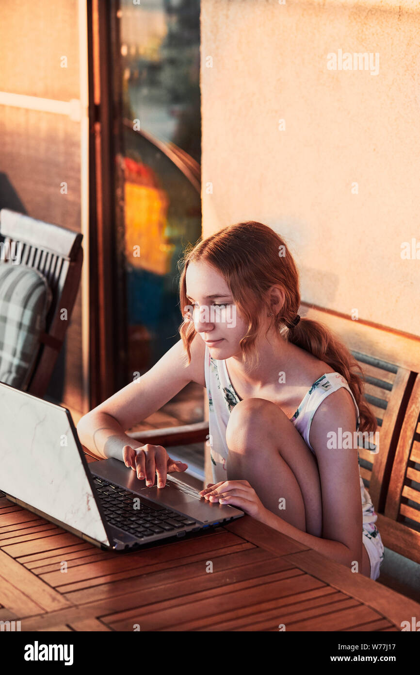Woman working at home, using portable computer, sitting on patio on summer day Stock Photo