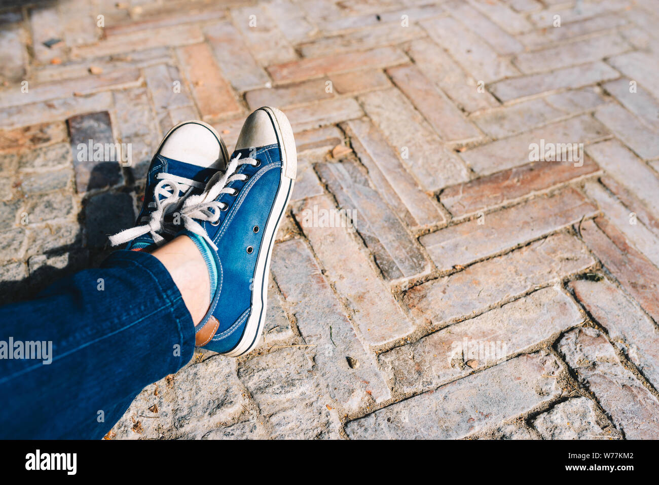 Foot and legs seen from above on a brick, rustic background. Selfie of  sneakers on the floor great for any use Stock Photo - Alamy