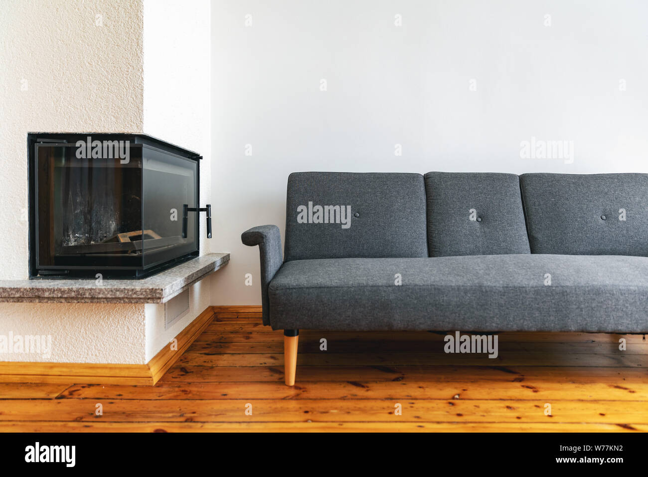 modern bright interior with fireplace and gray sofa on natural wood plank floor Stock Photo