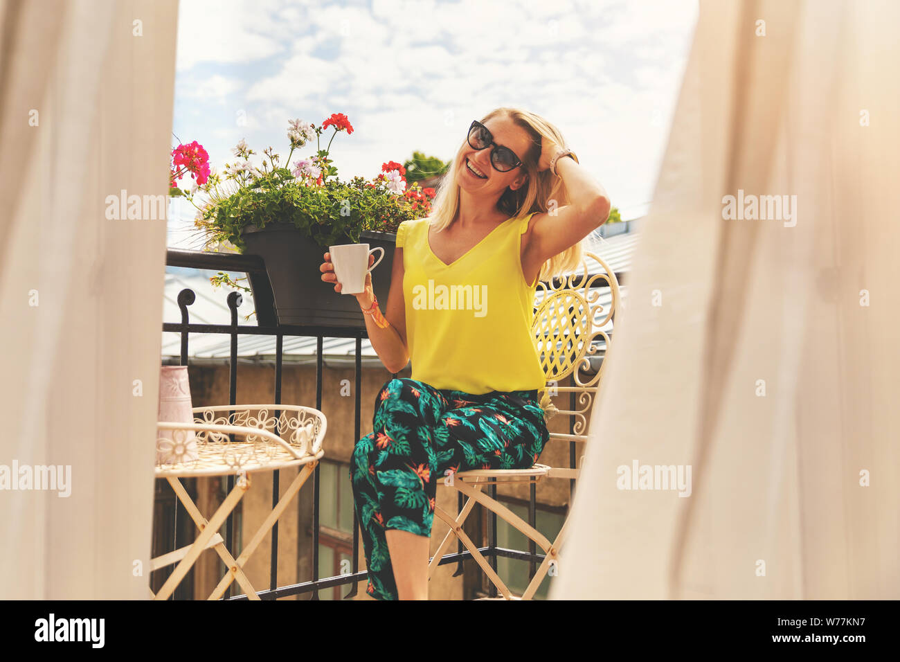 attractive smiling girl relaxing on balcony and having breakfast coffee Stock Photo