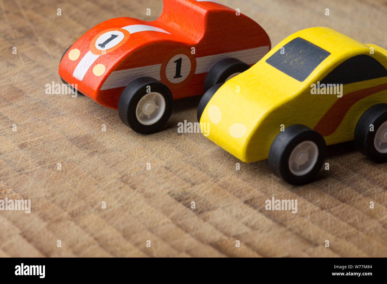 Red and yellow tiny toy vintage car close up on a wooden background ...