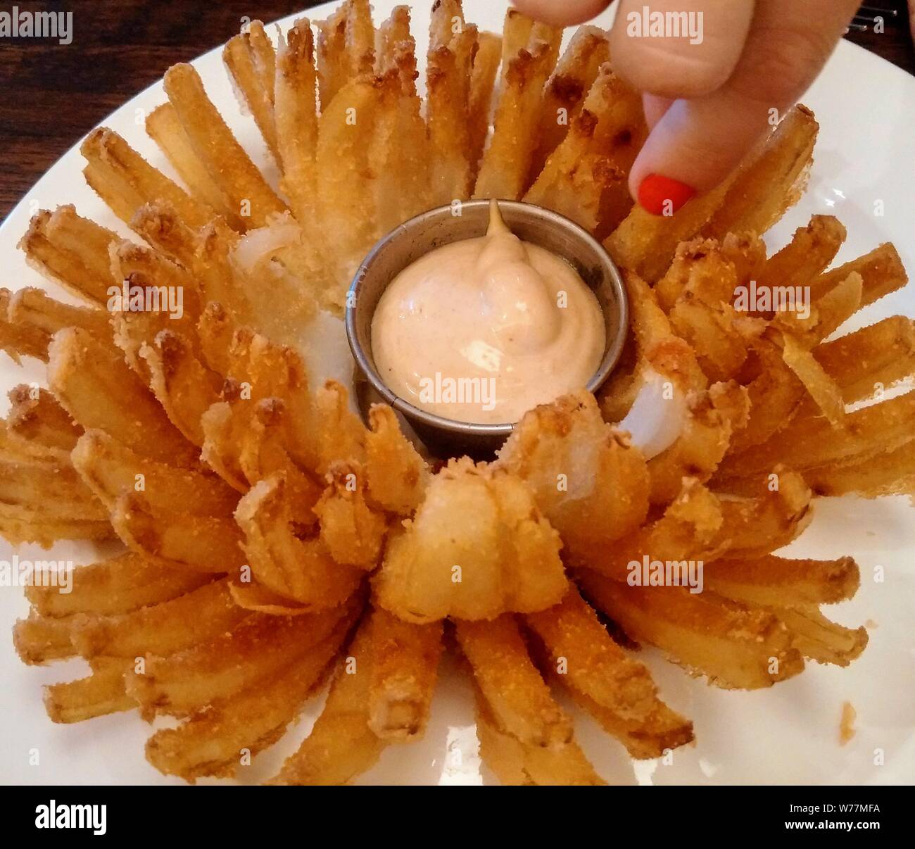 Deep fried chrysanthemum onion with ladies hand and dip Stock Photo Alamy