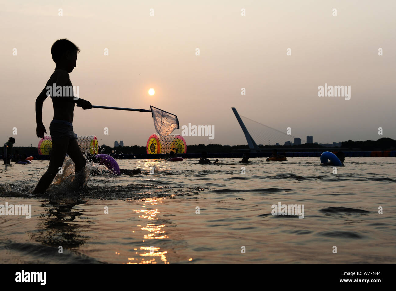 (190805) -- HARBIN, Aug. 5, 2019 (Xinhua) -- A kid plays along the Songhua River in Harbin, capital of northeast China's Heilongjiang Province. Attracted by the coolness in summer, many tourists come to Harbin for vacation. Meanwhile, Harbin is a city of music for the locals who got in touch with European classical music in an earlier time in China. With the cool summer and rich culture, Harbin received 36.23 million tourists and made revenue of 60.7 billion yuan (8.6 billion U.S. dollars) in the summer of 2018. (Xinhua/Wang Jianwei) Stock Photo