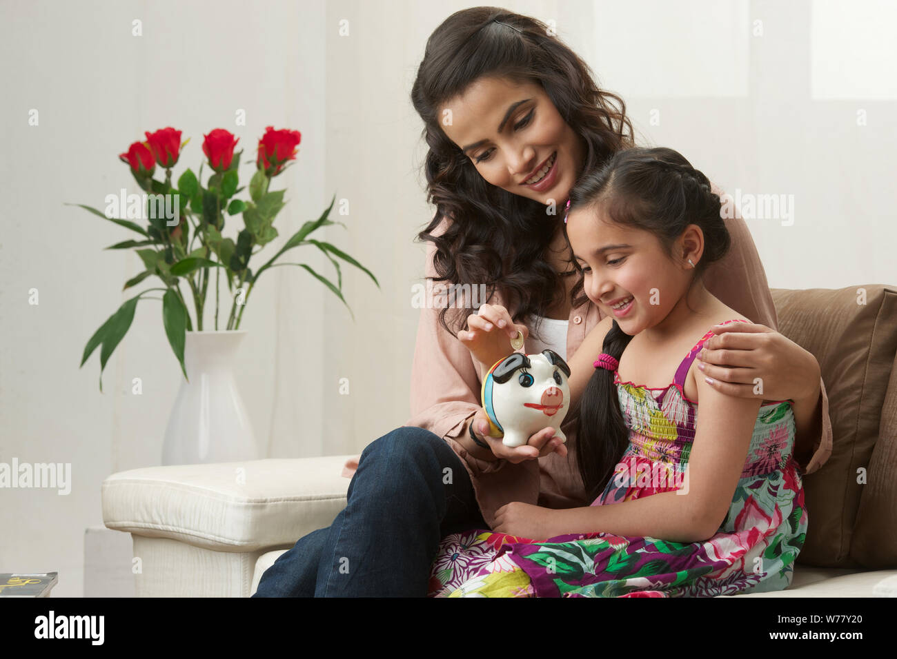 Girl putting coin into a piggy bank with her mother Stock Photo - Alamy