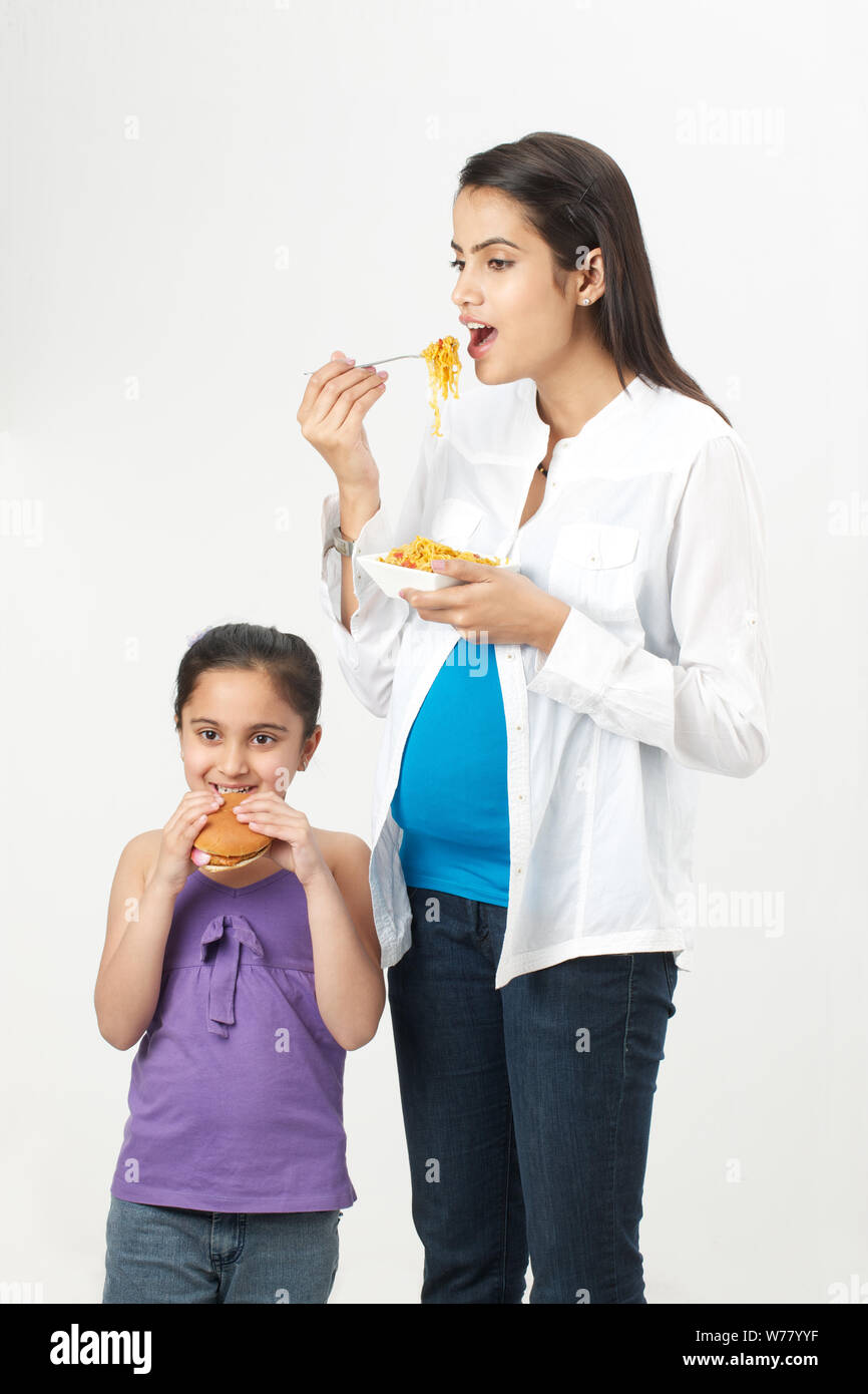 Pregnant woman and her daughter eating fast food Stock Photo