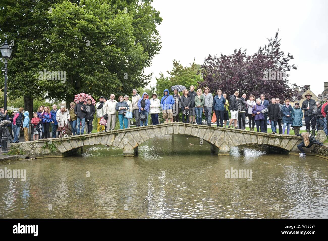 A British tradition, river football at Bourton-on-the-Water, Cotswolds August 2015. The match is held every August Bank Holiday. The game is a five-a-side football match, but in the River Windrush that runs through the town. Residents and visitors line the waters edge and bridges to get the best seats, but risk getting a soaking if the action comes too close. In 2015 British celebrithy, Griff Rhys Jones, took part during the filming for A Great British Adventure. Credit: Michael Scott/Alamy Live News Stock Photo