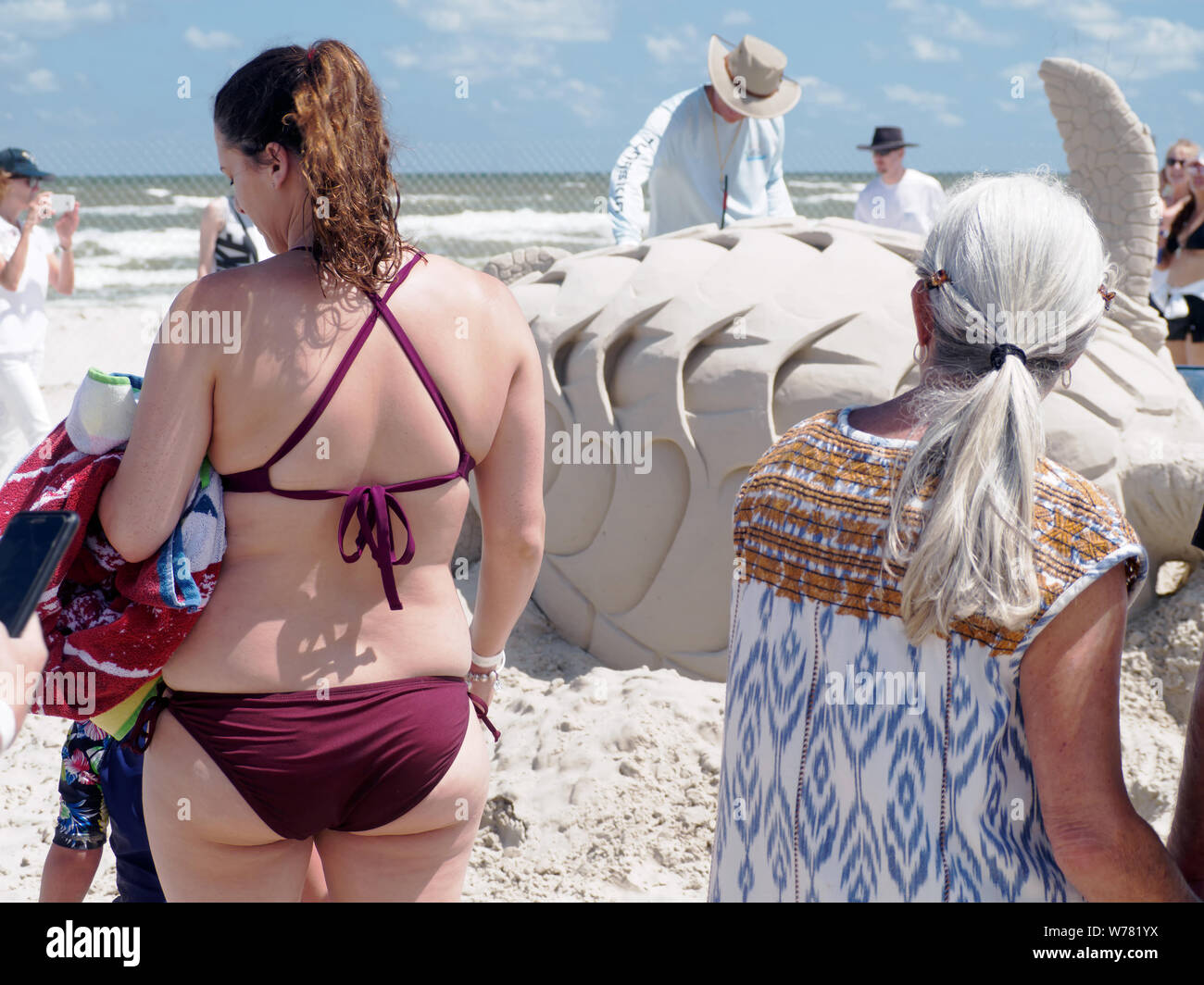 Caucasian woman in maroon bikini, from behind, is among the visitors to