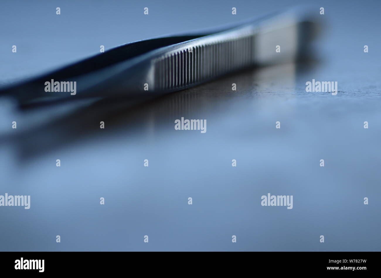 ER: A pair of tweezers to be utilized in an operation sits on a surgical tray. Stock Photo