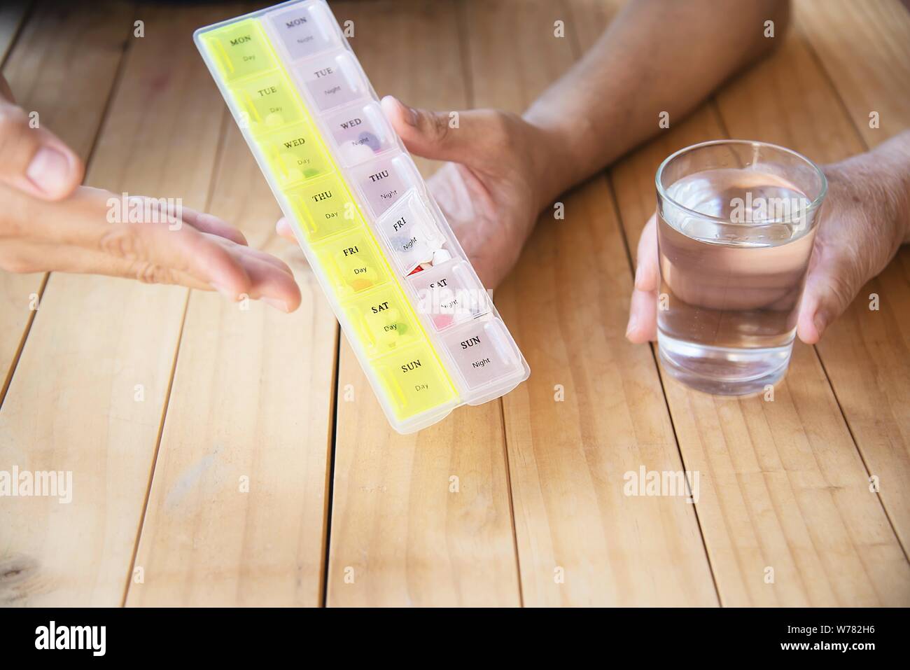 Doctor is assist patient to eat medicine tablet in pillbox correctly - people medical concept Stock Photo