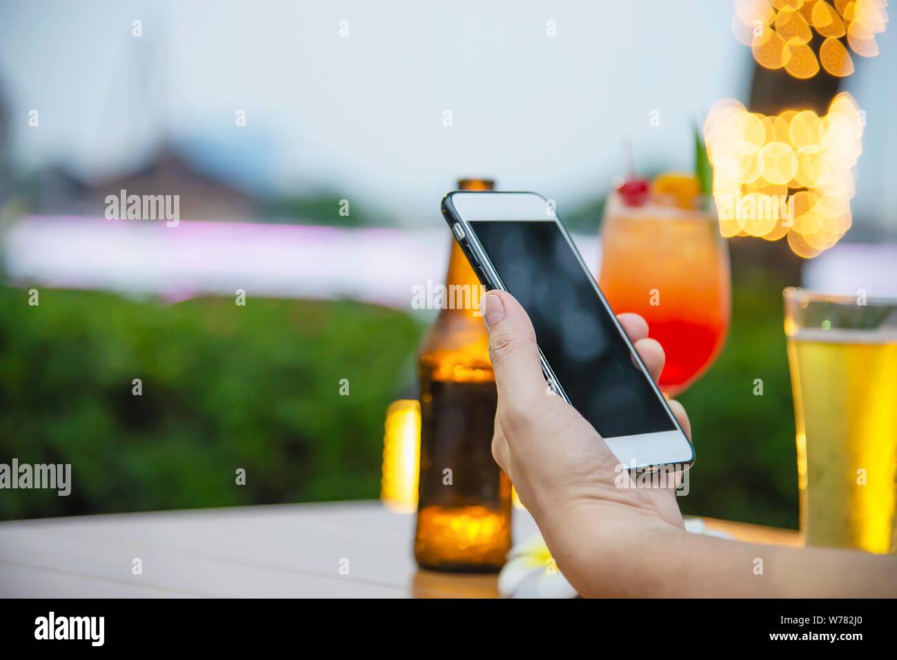 Man using mobile during happy time relax in restaurant with softdrink and green garden background - people relax with technology lifestyle concept Stock Photo