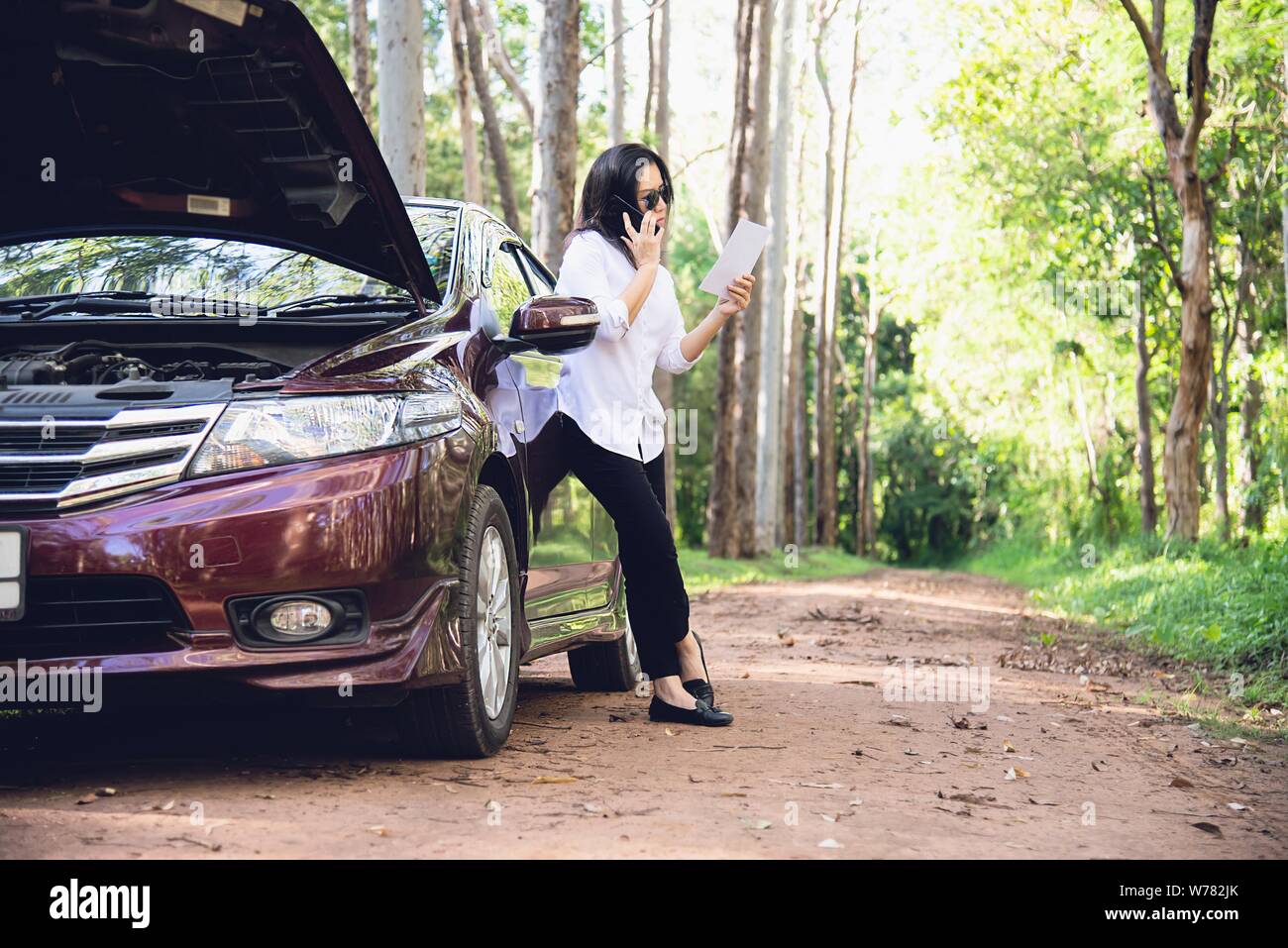 Asian woman calling repairman or insurance staff to fix a car engine ...