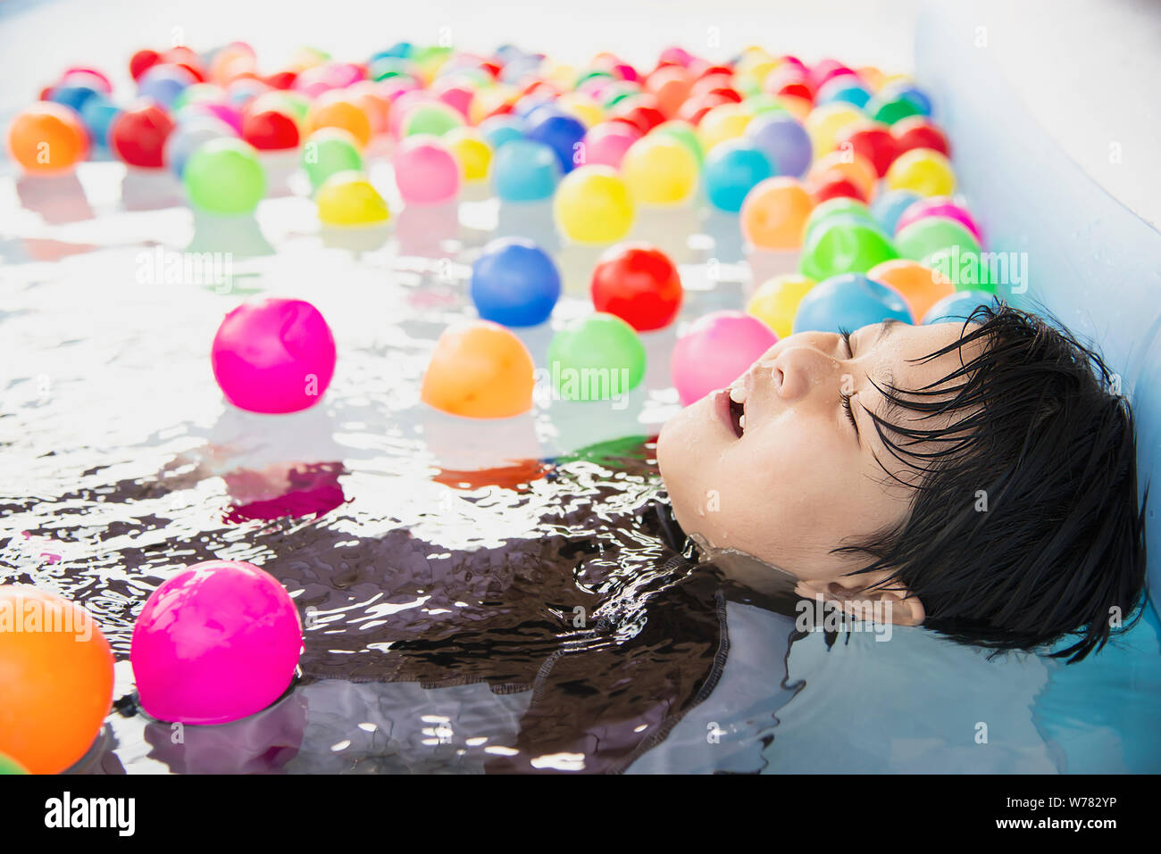 Boy playing with colourful ball in small swimming pool toy - happy boy in water pool toy concept Stock Photo