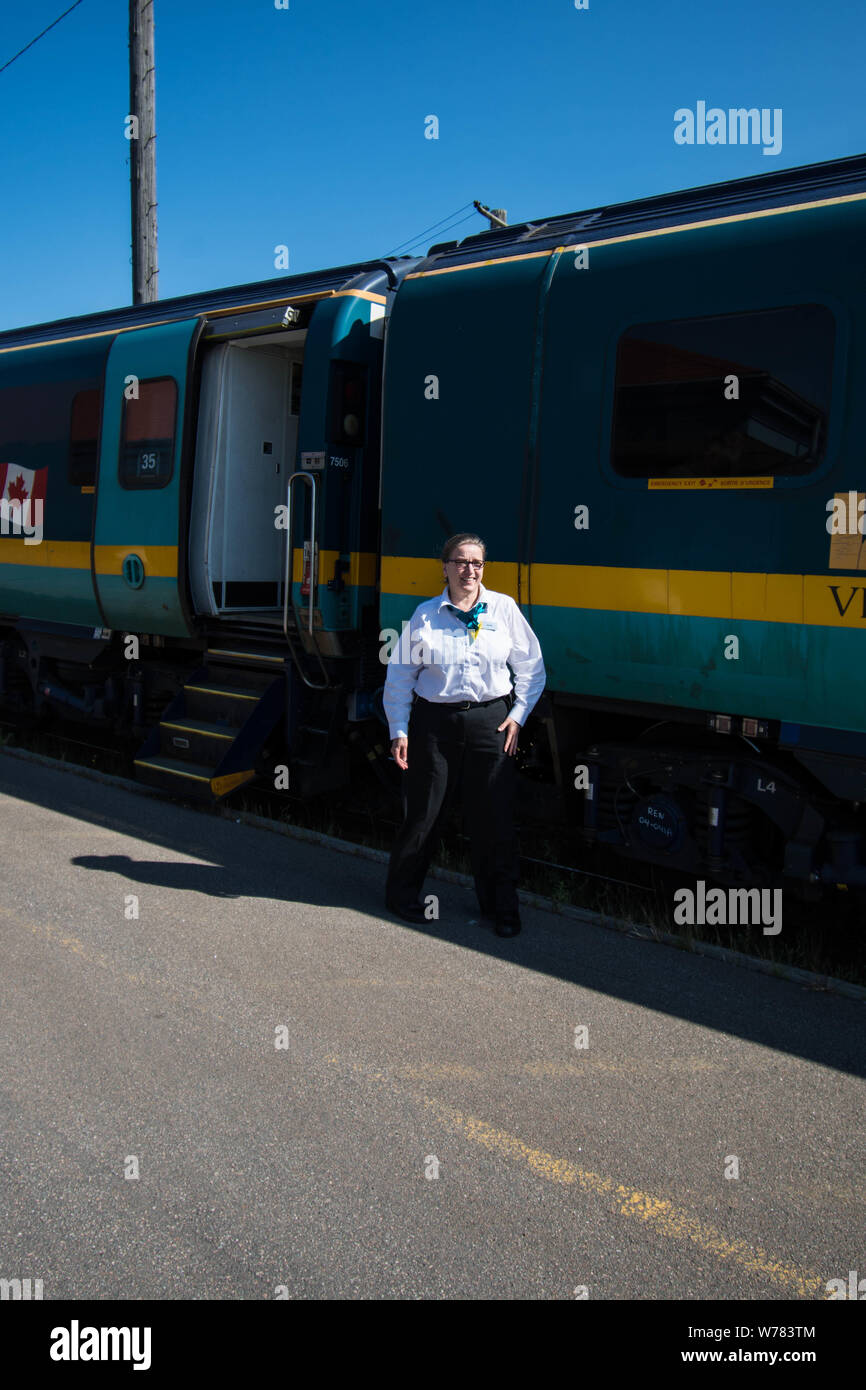 Train Guard for the Toronto to Halifax Nova Scotia train at Halifax station standing departing ready go stripe yellow green diesel commuter steps Stock Photo