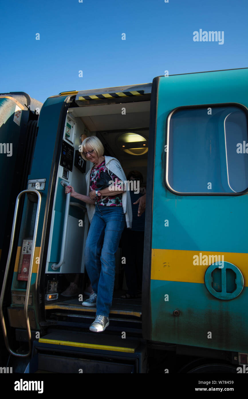 Train Halifax Nova Scotia Canada tourist stepping down carriage door step sliding  diesel commuter sleeper stripe stripes yellow blonde girl green Stock Photo